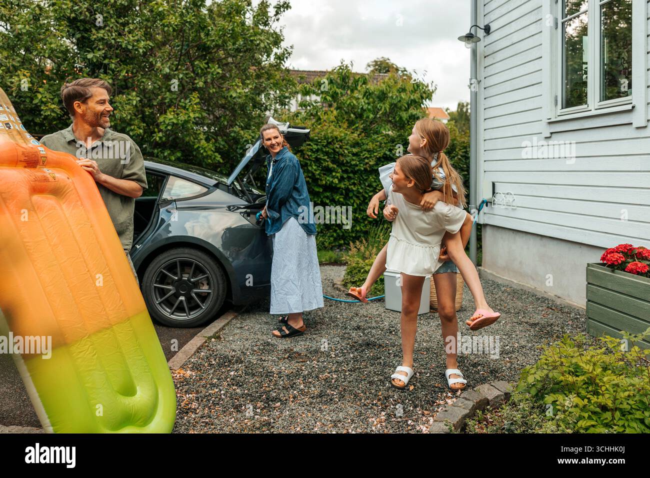Les parents regardant la fille piggyback soeur dans la cour arrière Banque D'Images