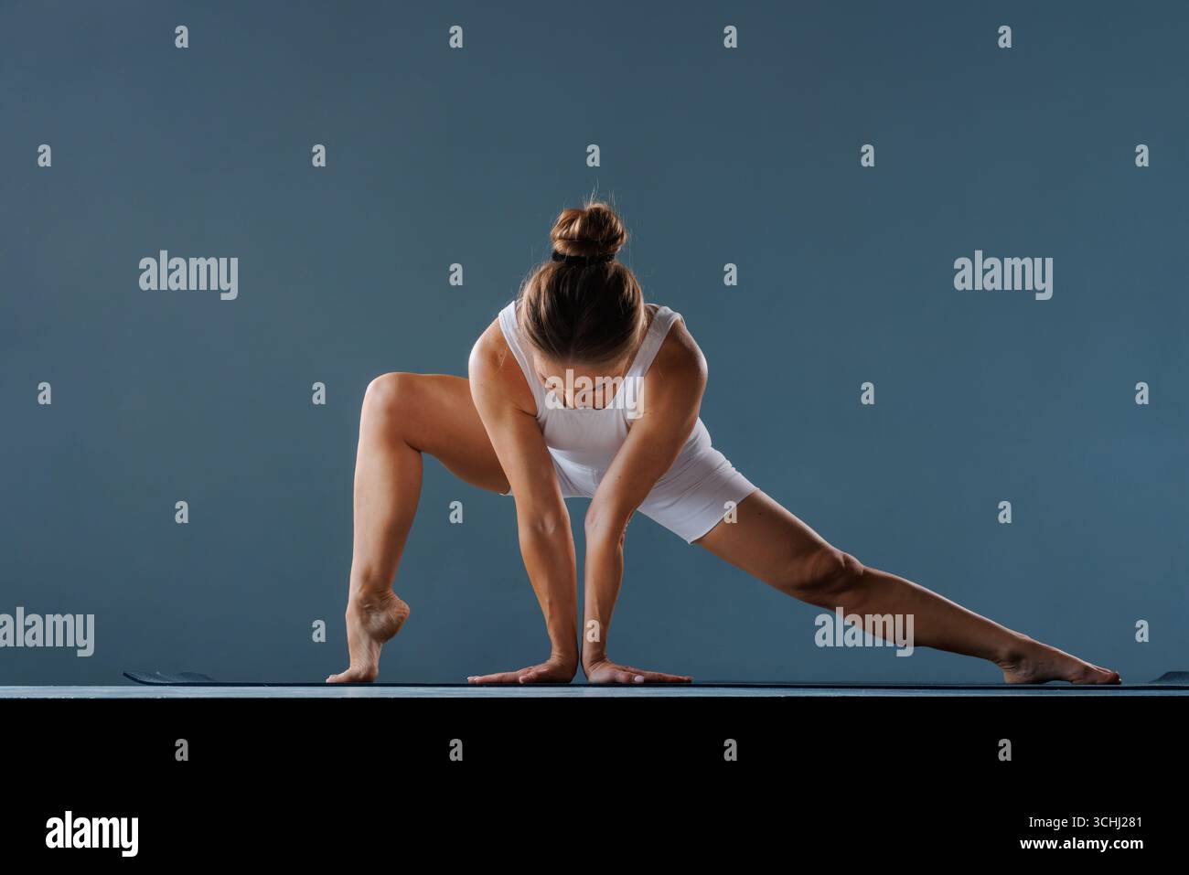 Femme en forme faisant une pose de yoga stretch de jambe large en studio, développant la flexibilité de la hanche, la force du tronc et l'équilibre. Banque D'Images