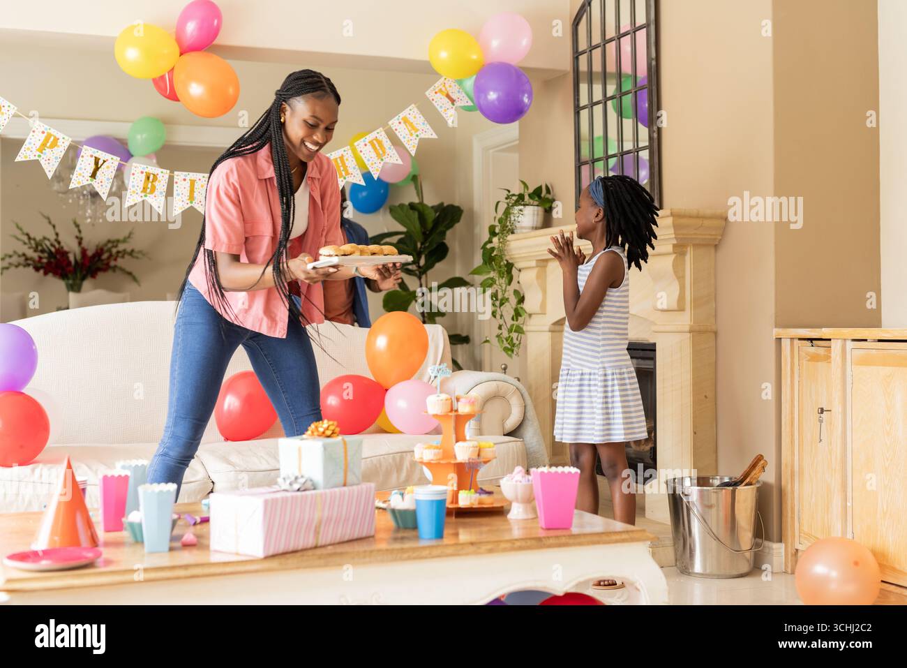Célébration d'anniversaire, mère afro-américaine et enfant avec des cupcakes et des décorations Banque D'Images
