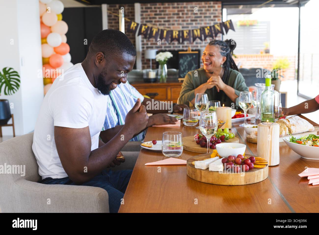 Célébration de la retraite, groupe diversifié appréciant la nourriture et le rire à la maison rassemblement Banque D'Images