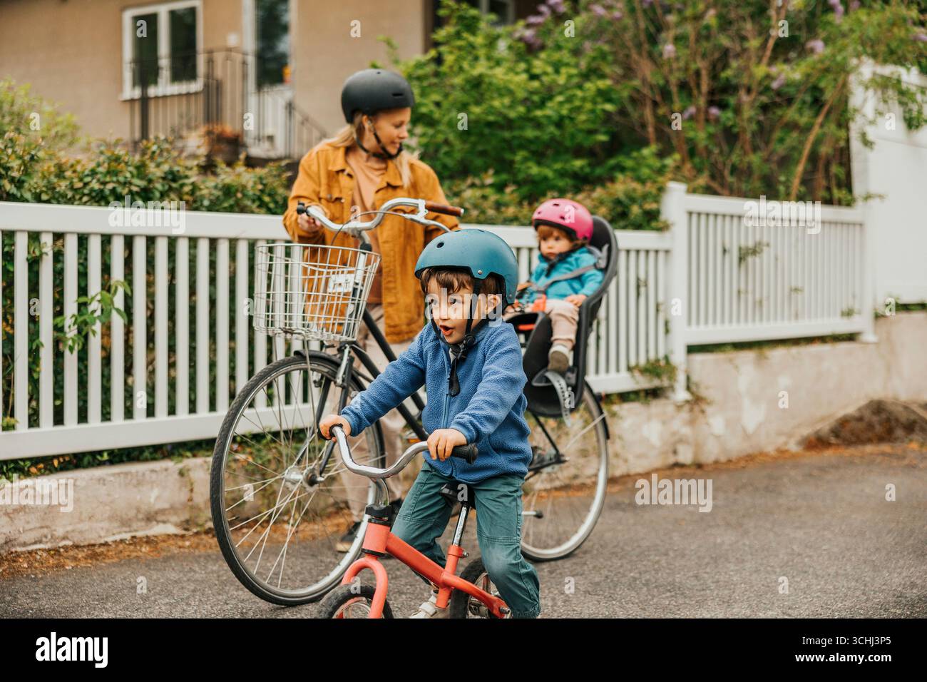 Garçon portant casque vélo d'équilibre d'équitation avec la famille sur le sentier pédestre Banque D'Images