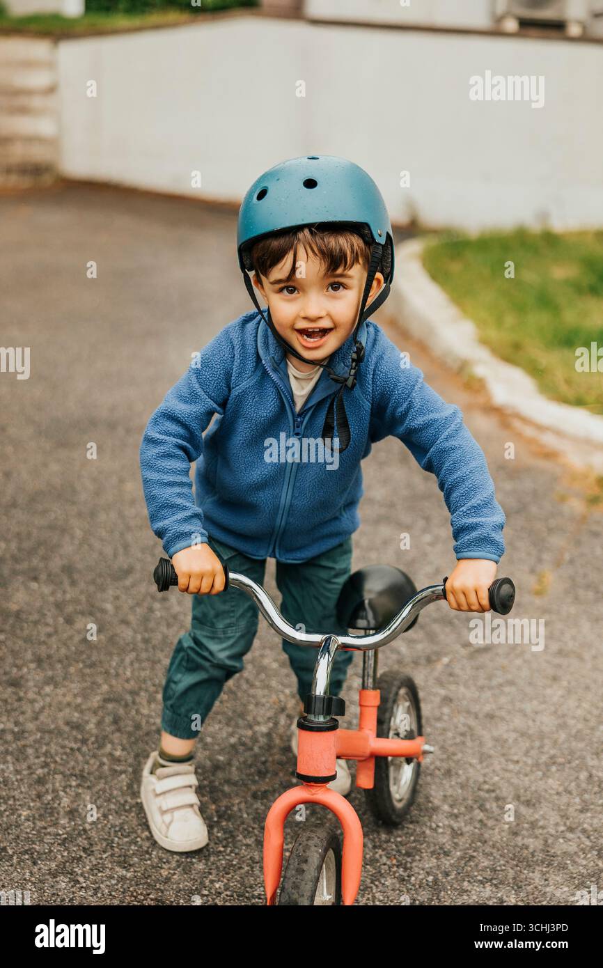 Portrait de garçon mignon avec vélo d'équilibre debout sur la route Banque D'Images