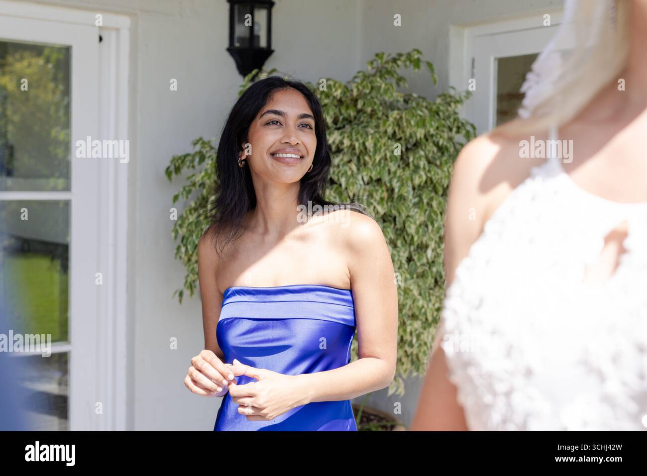Femme souriante en robe bleue appréciant la célébration de mariage en plein air avec des amis Banque D'Images