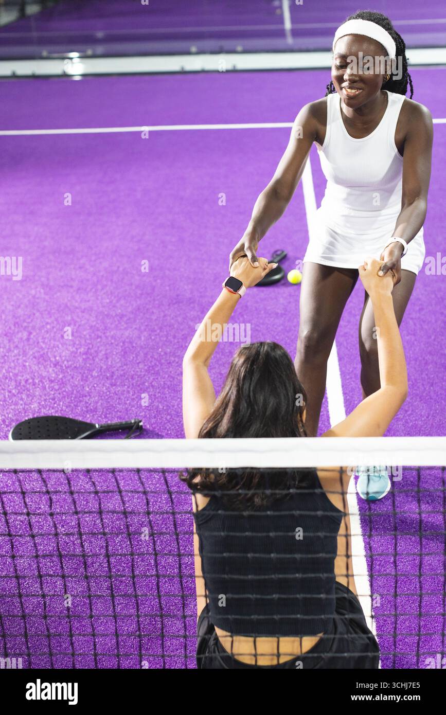 Diverses joueuses de tennis féminines s'aidant les unes les autres au filet sur la raquette de court pourpre, balle Banque D'Images