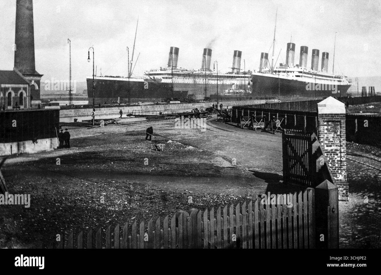 Titanic a sa coque peinte à moitié. Il y a très peu d'espace entre les deux navires, ils sont séparés par quelques remorqueurs. Olympic vient de quitter le quai de gravure. Elle doit être reculée avant que Titanic puisse être déplacé dans le quai de gravure. Mars 1912 Banque D'Images