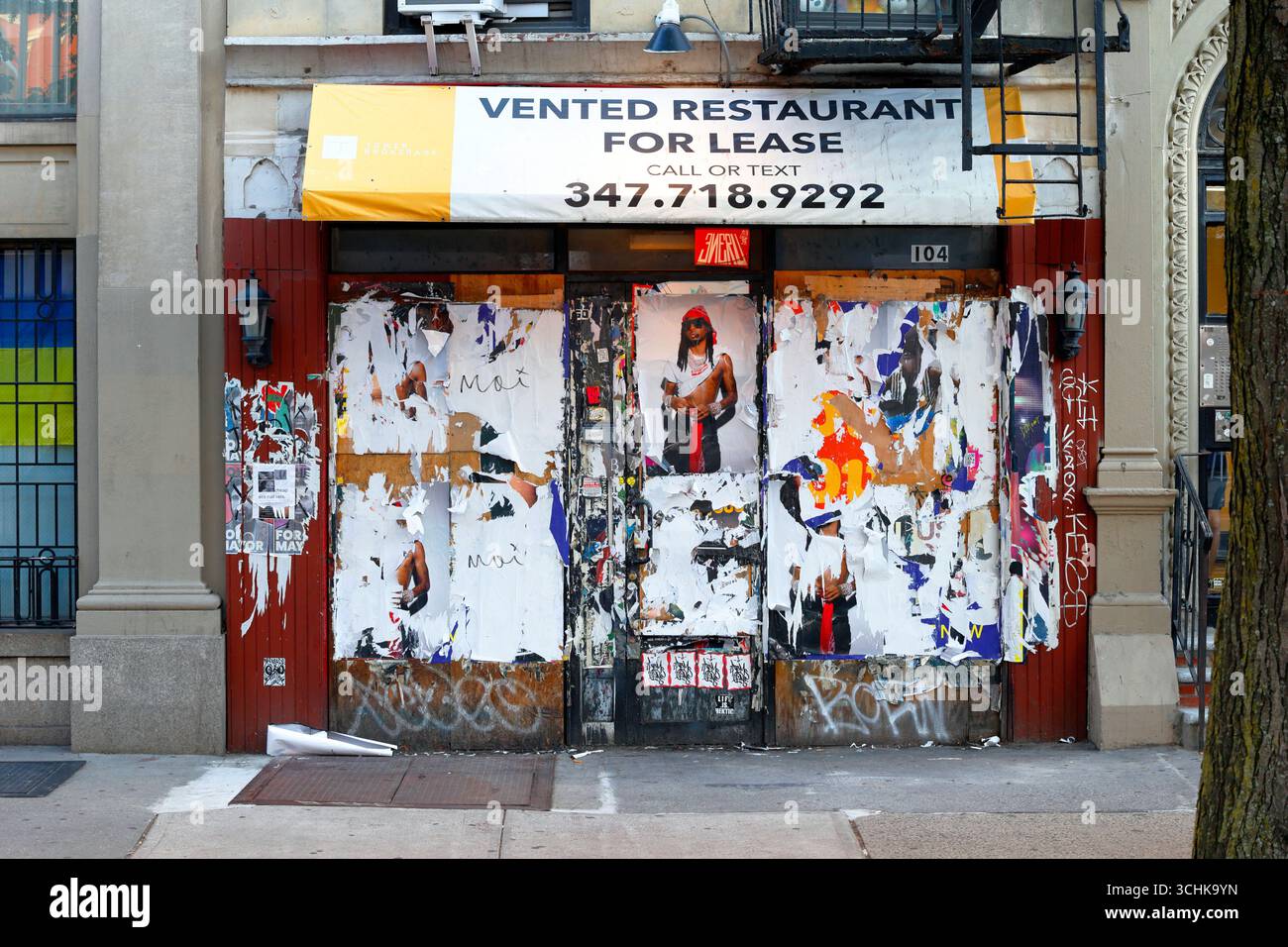 Un espace de restaurant vide, fermé et arboré à louer avec affiches et graffitis sur le devant, à New York Banque D'Images