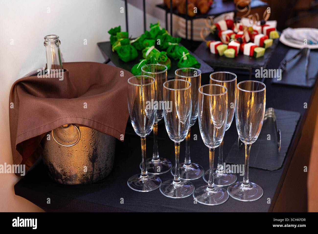 Une configuration de rassemblement avec des verres à champagne, une bouteille fraîche et des collations appétissantes. parfait pour les fêtes ou les événements spéciaux avec une touche d'élégance. Banque D'Images
