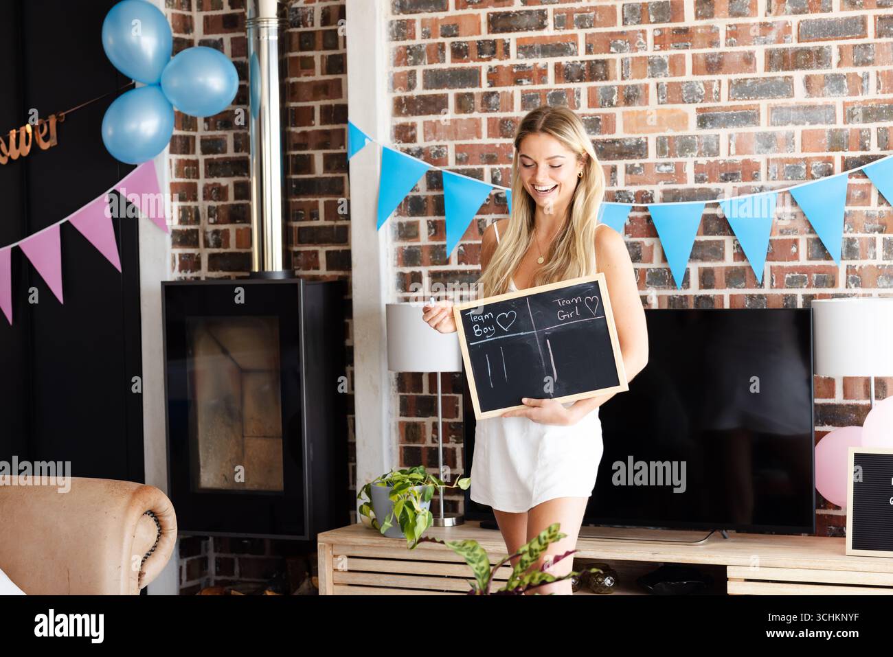 Douche de bébé, femme tenant un tableau noir à la fête de révélation de genre, souriant avec excitation Banque D'Images