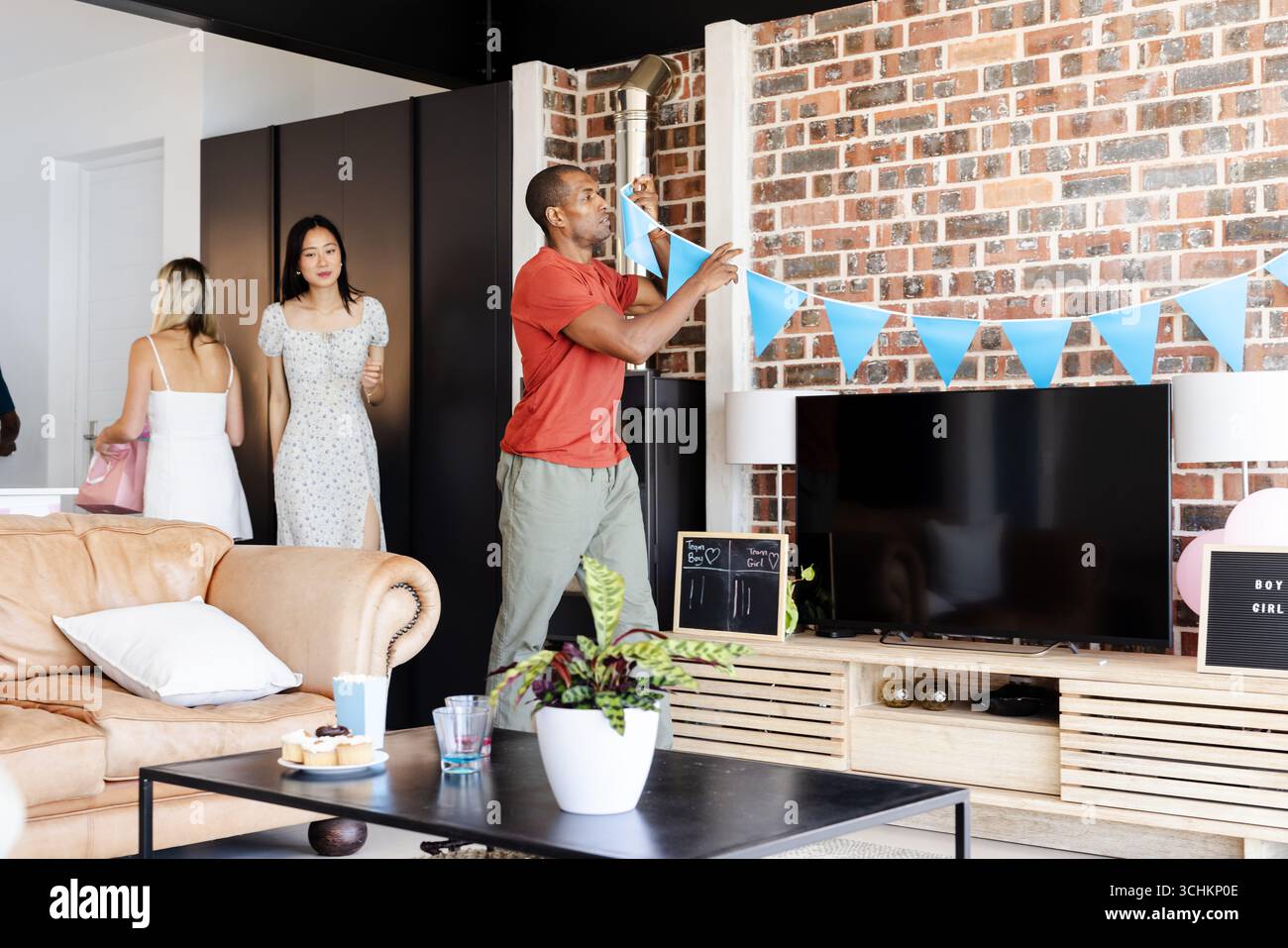 Douche de bébé, homme décorant le salon avec la banderole bleue pour la partie de révélation de genre, à la maison Banque D'Images