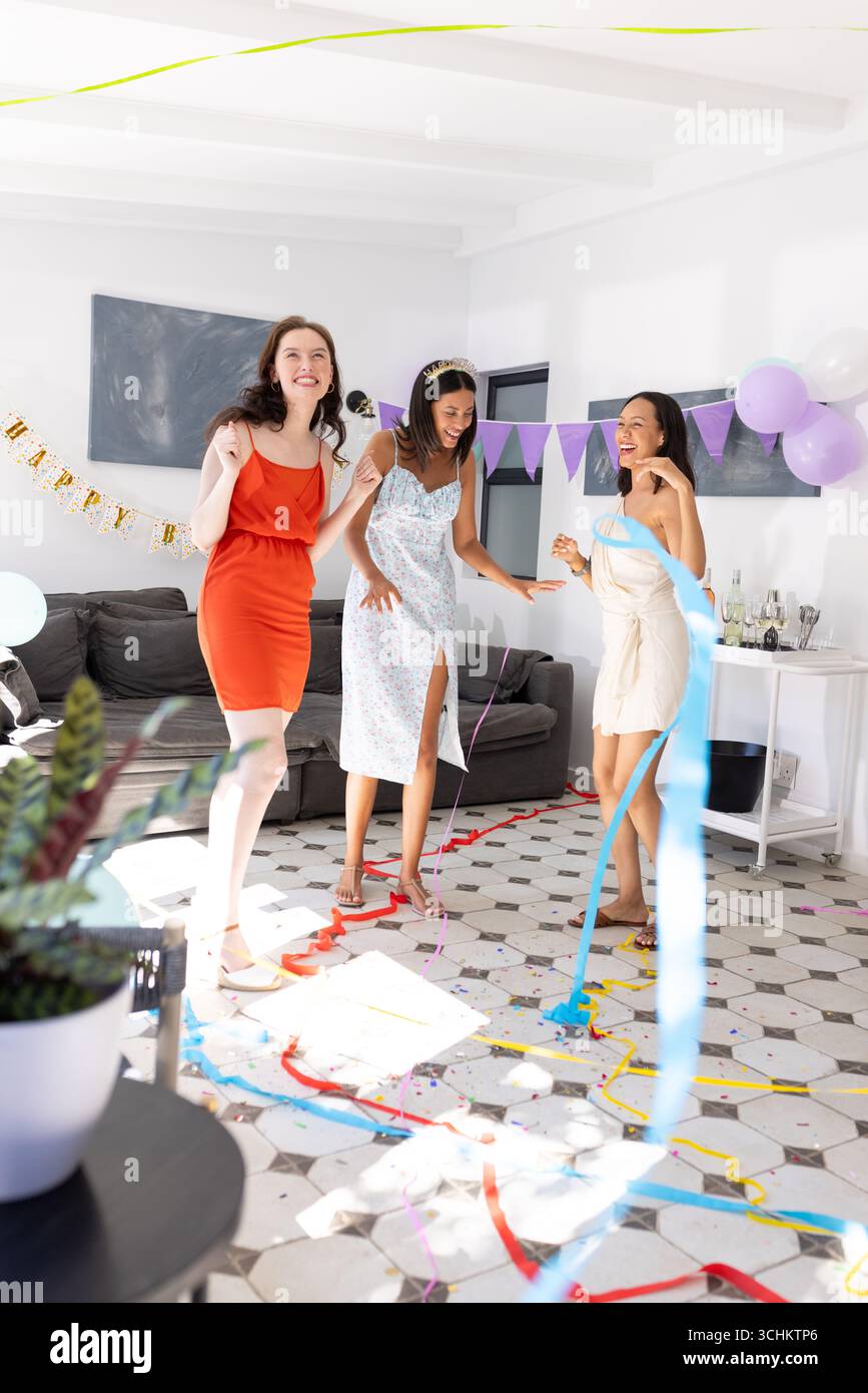 Dansant joyeusement dans le salon ensoleillé, trois jeunes femmes célèbrent ensemble Banque D'Images