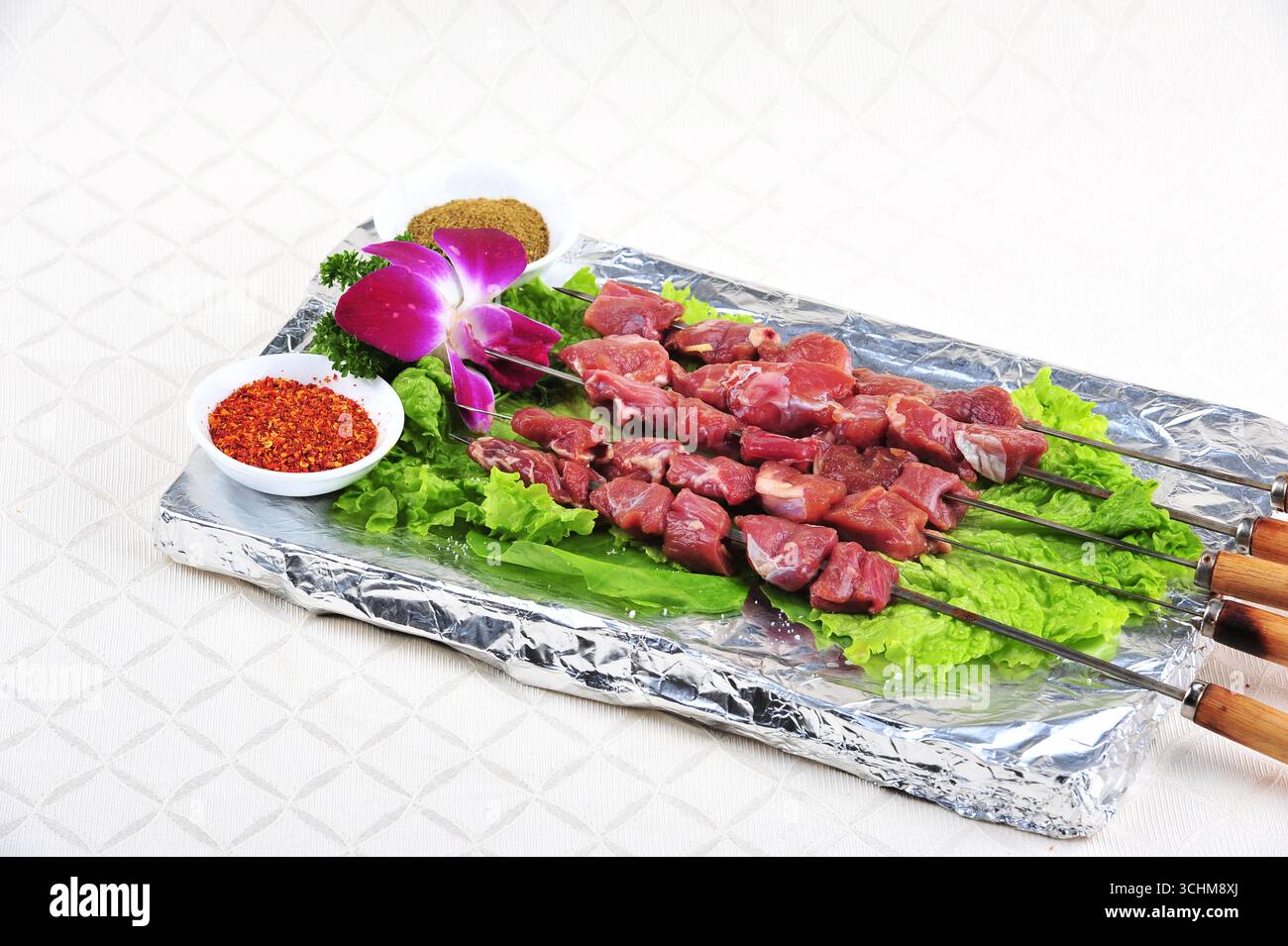 Brochettes d'agneau cru avec piment et cumin sur plateau en feuille Banque D'Images