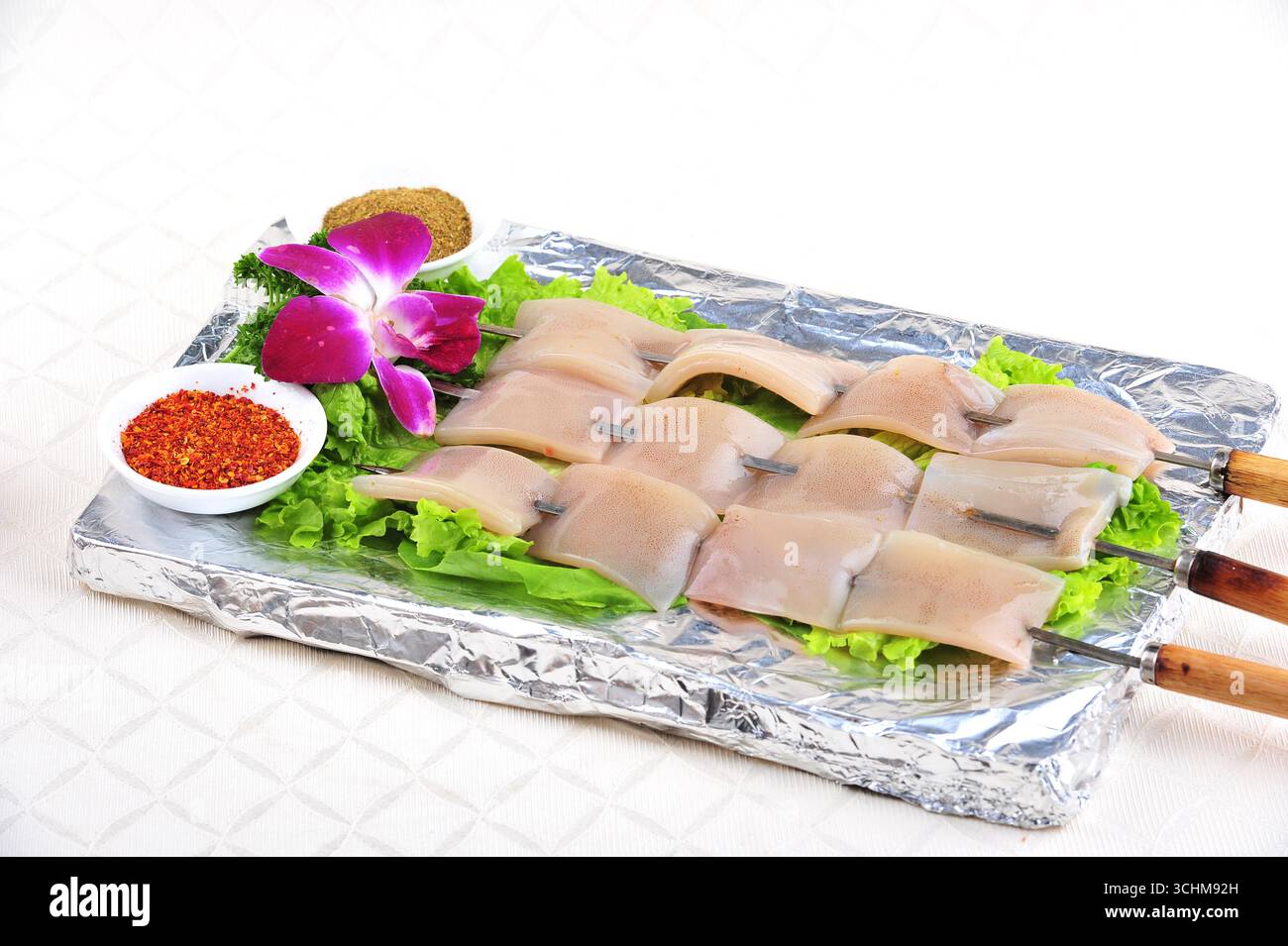 Brochettes de calmars avec piment et cumin sur un plateau en feuille Banque D'Images