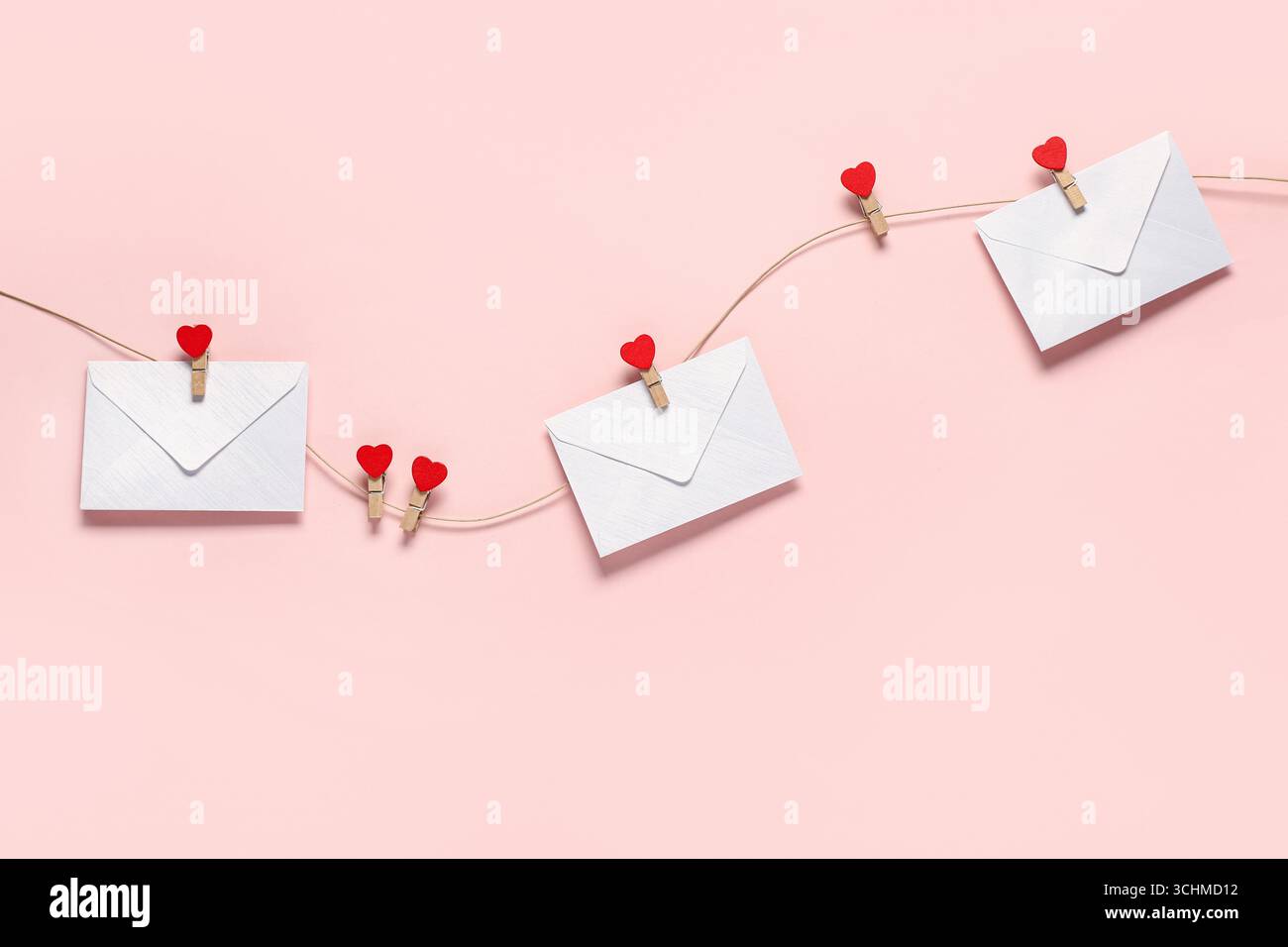 Enveloppes suspendues sur corde sur fond de couleur. Célébration de la Saint-Valentin Banque D'Images