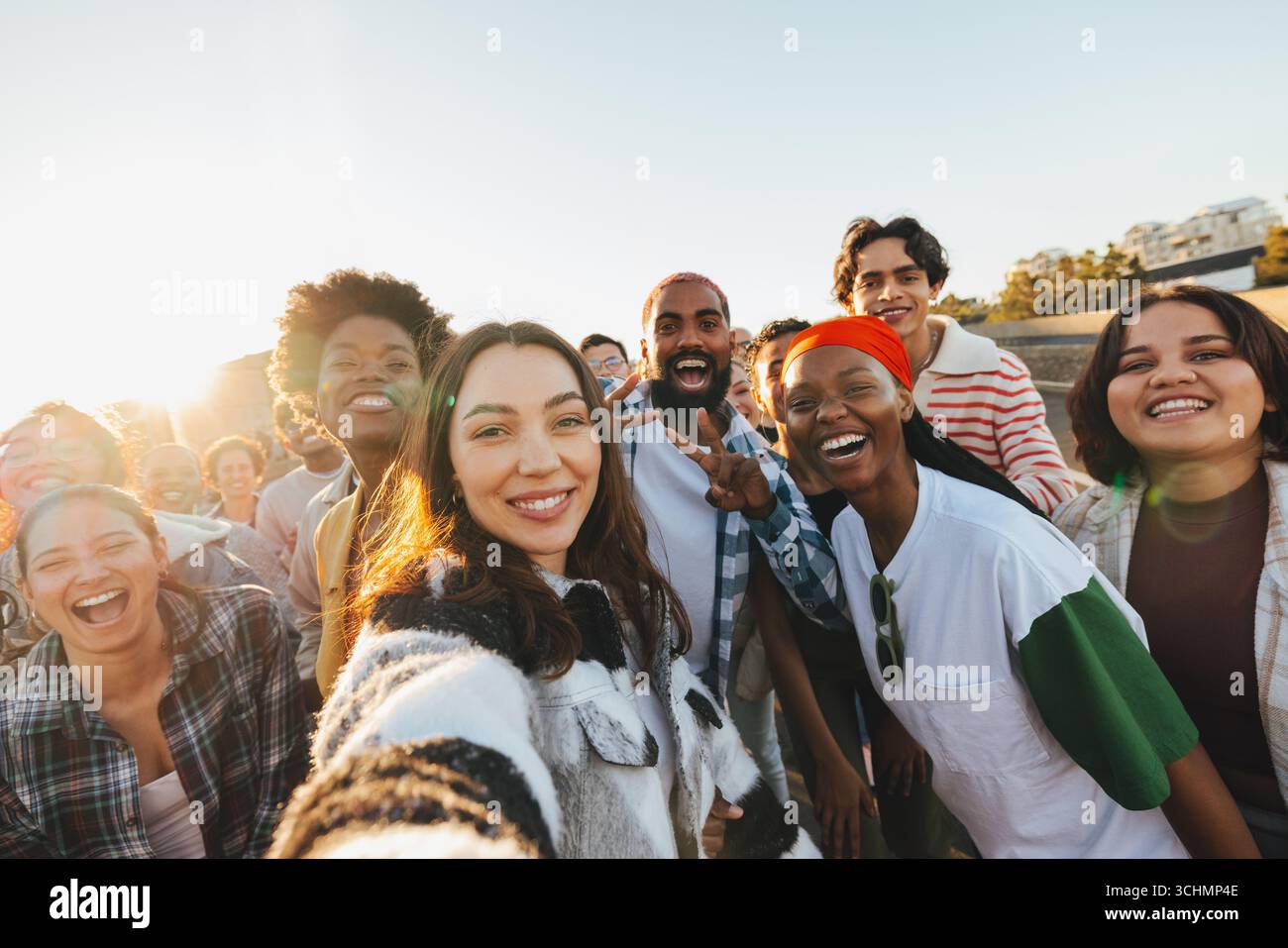 Un groupe de jeunes adultes heureux et diversifiés souriant ensemble à l'extérieur dans la lumière du soleil, capturant un moment de connexion et d'amitiés. L'atmosphère Banque D'Images