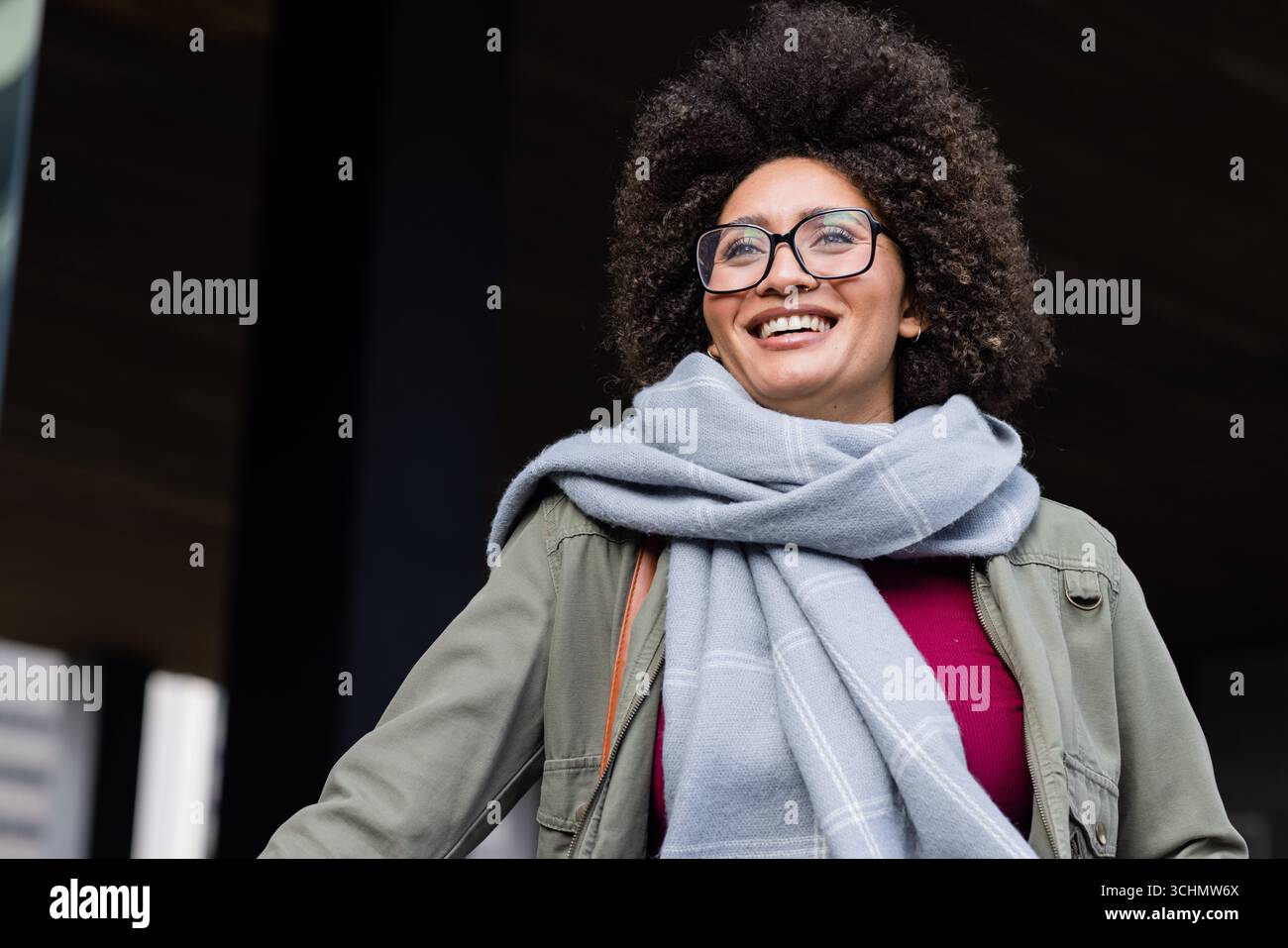 Femme afro-américaine debout sous la canopée en veste olive, écharpe grise, lunettes, espace copie Banque D'Images