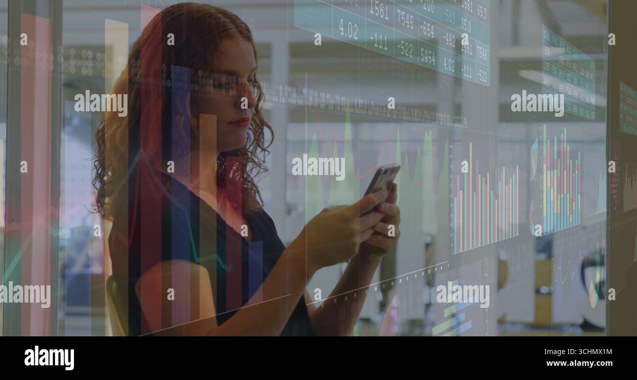 Tenant smartphone, analyste projetant des graphiques de données dans un bureau ouvert, avec des cloisons en verre Banque D'Images