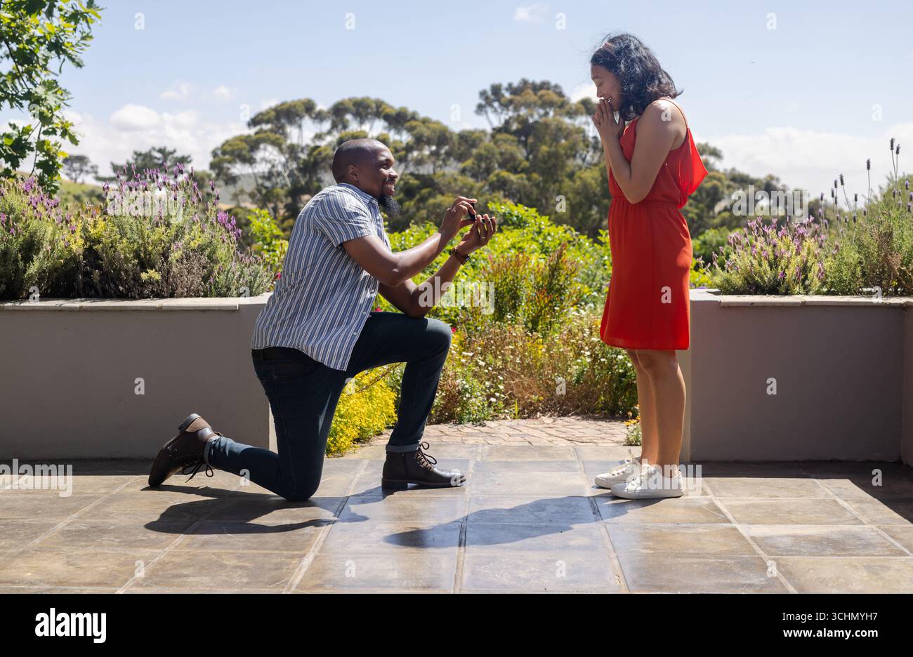 Homme proposant de surprendre femme dans le jardin, à la fois souriant et joyeux Banque D'Images