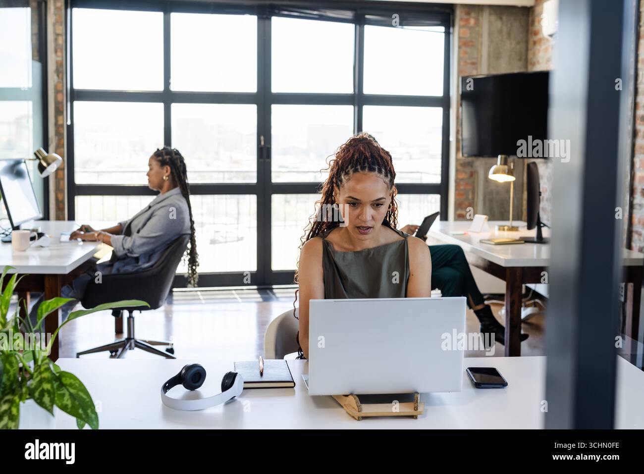 Focalisé diverses femmes professionnelles travaillant sur des ordinateurs portables dans un bureau moderne, collaborant sur des projets Banque D'Images