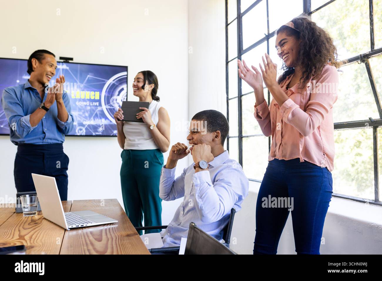 Équipe d'affaires diversifiée célébrant le succès au bureau, souriant et applaudissant ensemble Banque D'Images