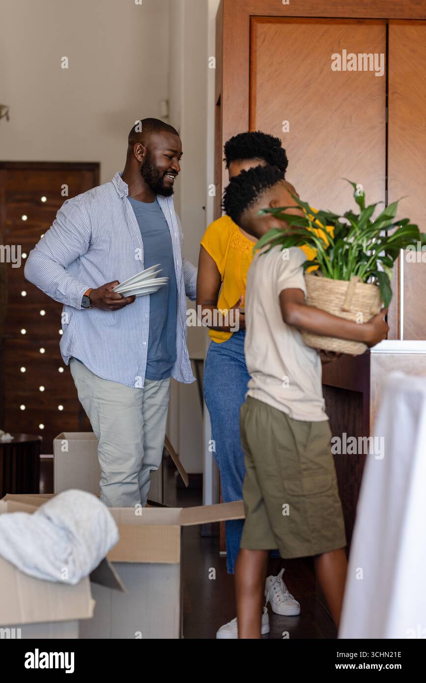 Famille déballer des boîtes à la maison, sourire et organiser un nouvel espace de vie Banque D'Images