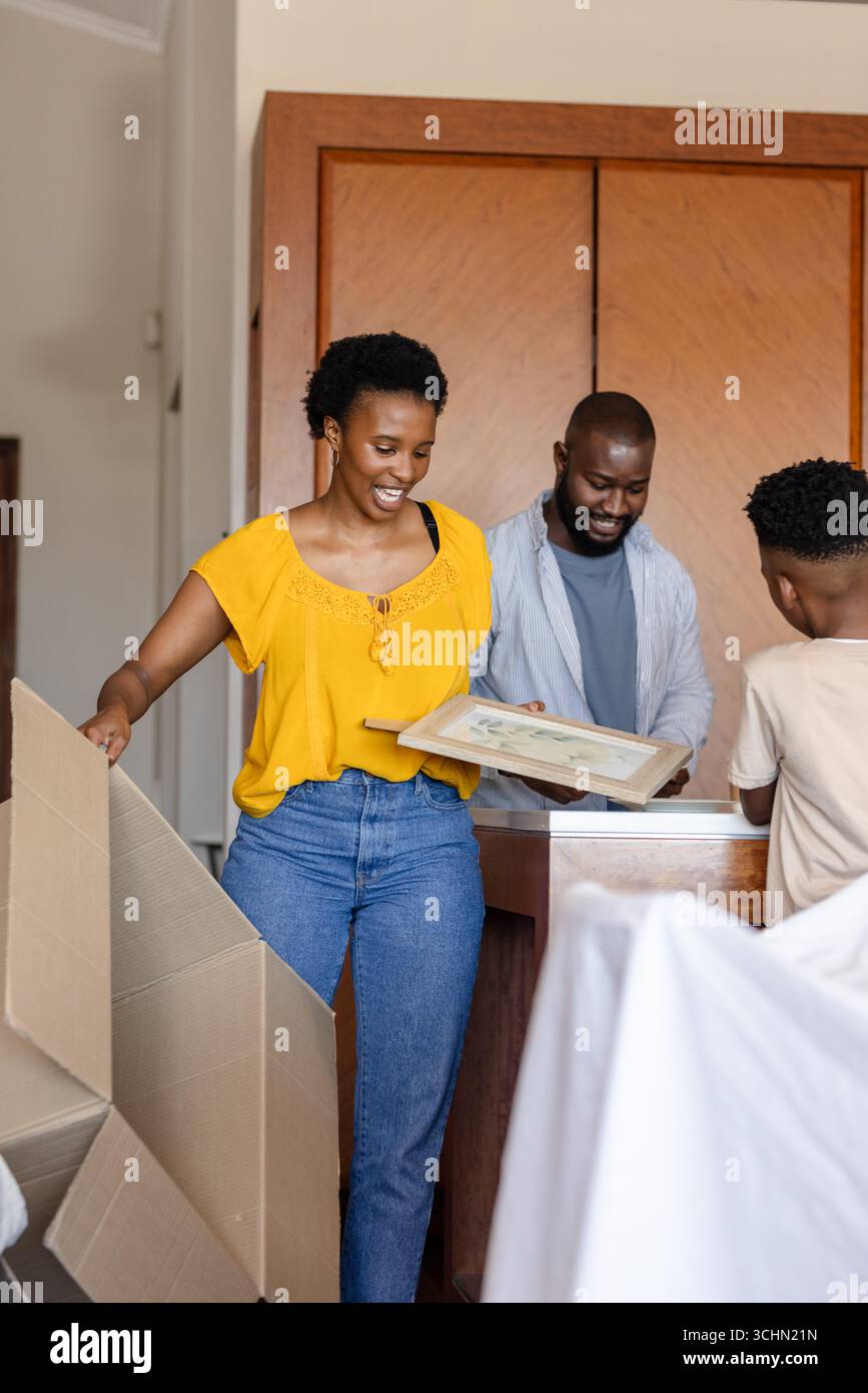 Famille déballer des boîtes à la maison, sourire et organiser un nouvel espace de vie Banque D'Images