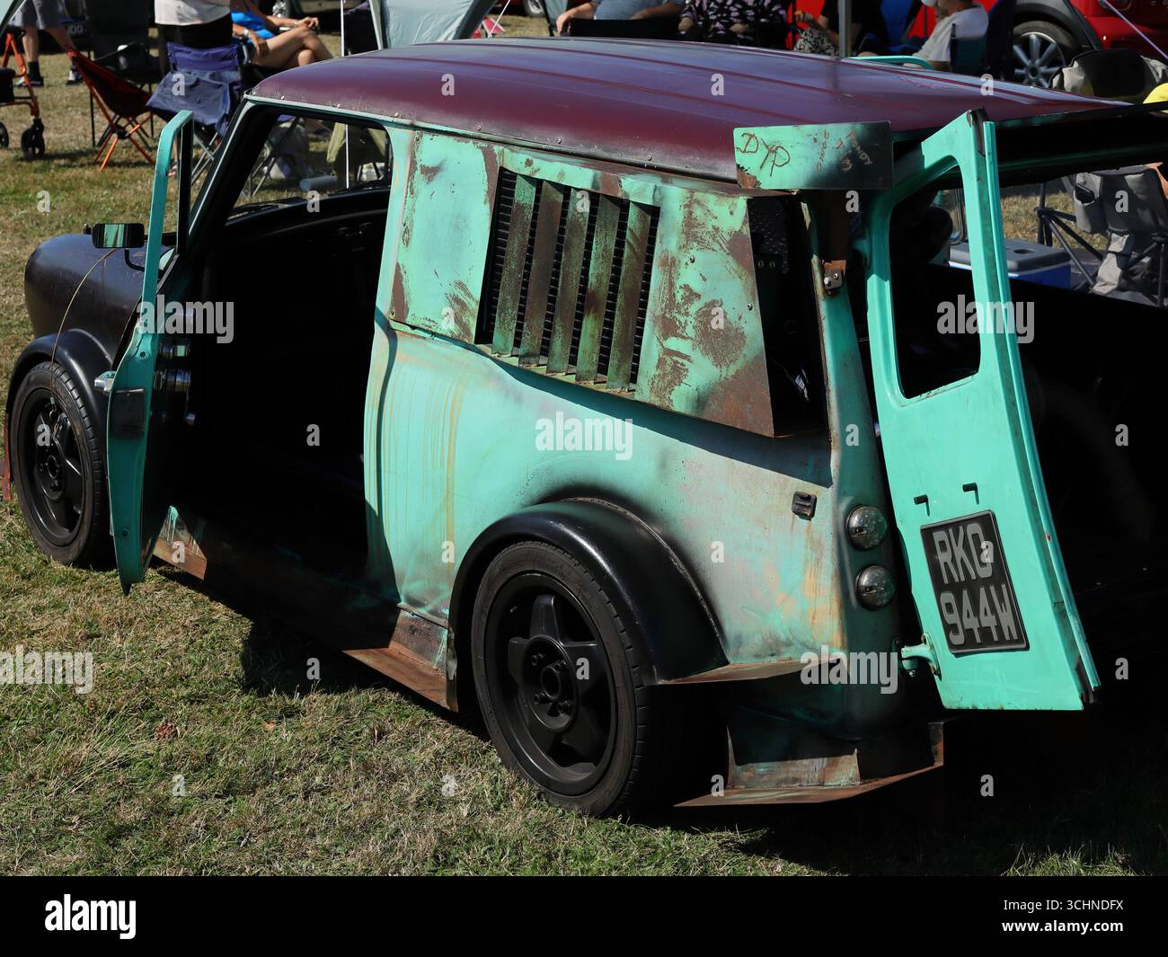 Cette image montre un Mini Clubman Estate de style patine très modifié lors du rallye automobile. Le véhicule a une carrosserie fortement rouillée et altérée, avec un travail de peinture vert délavé et marron. La porte arrière est ouverte et les jantes en alliage noir personnalisées de la voiture sont visibles. Illustration, éditorial : le rallye automobile de Stokes Bay à Gosport, Hampshire, Angleterre. 25 août 2025. Banque D'Images