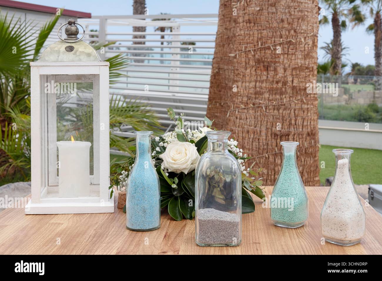Configuration de cérémonie de sable de mariage sur une table en bois à l'extérieur avec quatre bouteilles en verre transparent remplies de sable de couleur différente utilisé dans un rituel d'unité Banque D'Images