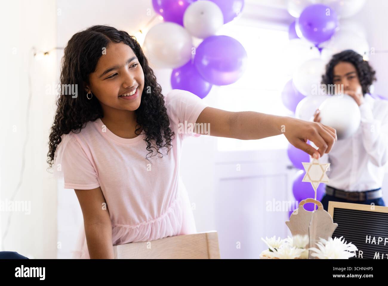 Famille diversifiée, fille souriante décorant pour la célébration avec Star of David et des ballons, à la maison Banque D'Images