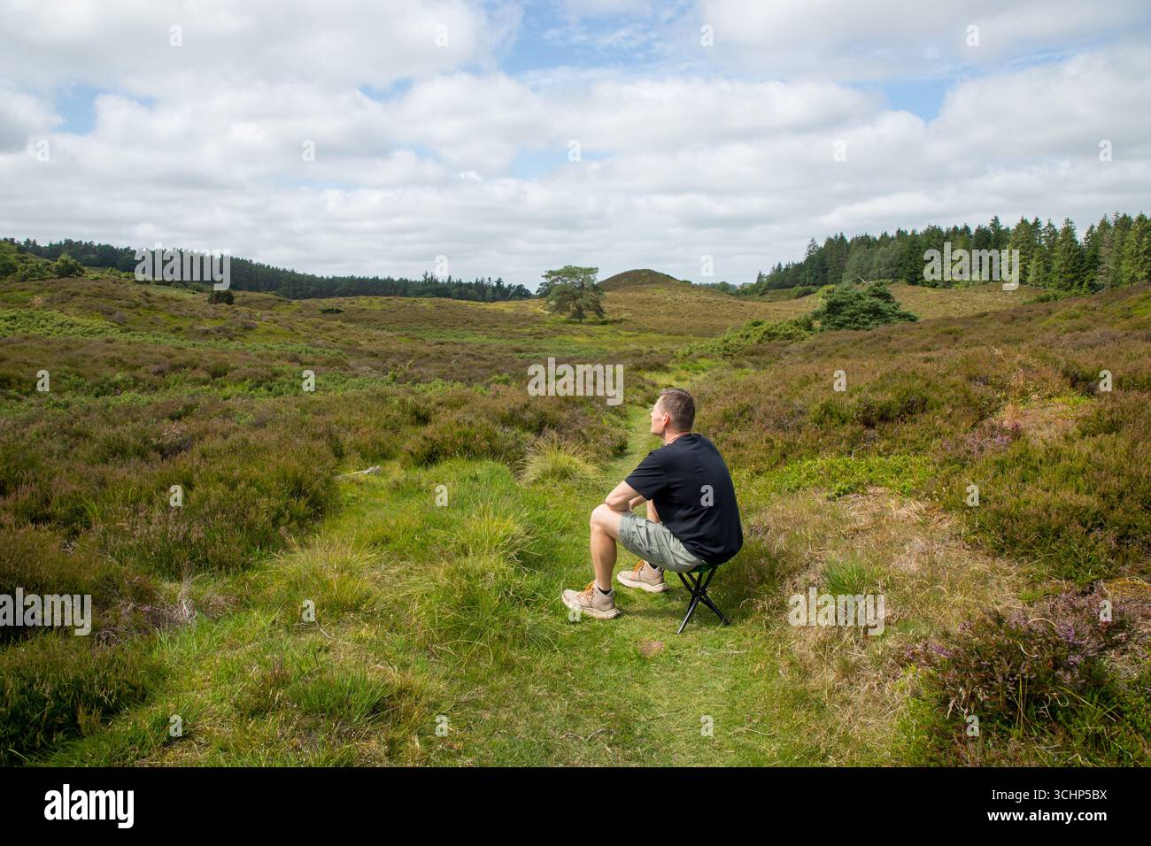 l'homme seul est assis tranquillement sur un tabouret dans le heatland dans la lumière du soleil se reposant et pensant, bien-être en plein air, l'homme seul dans la nature pensant Banque D'Images