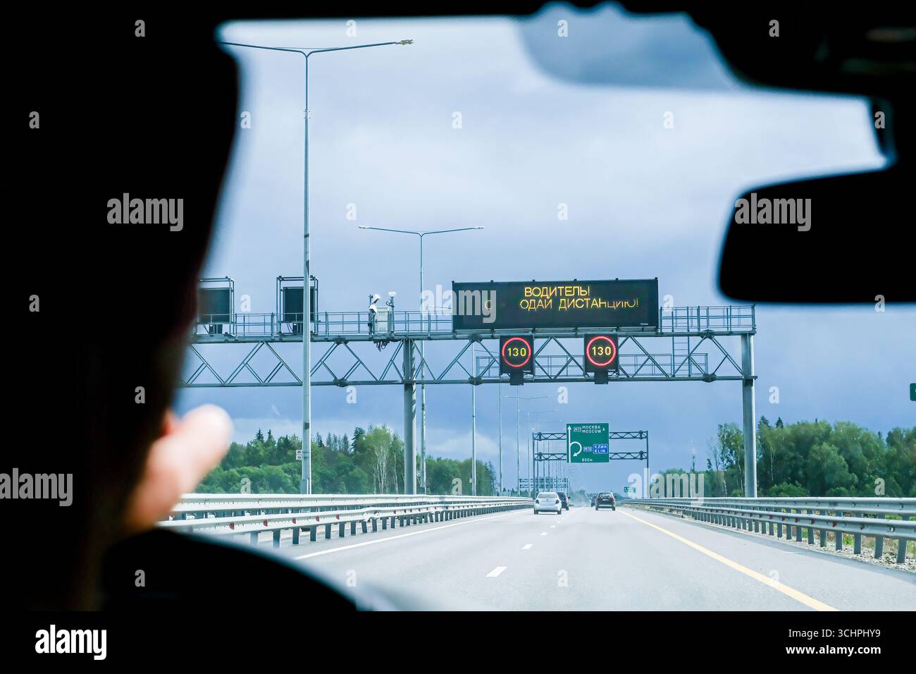 Moscou, Russie, 18.08.2025 homme conduisant une voiture sur une autoroute, regardant les panneaux de signalisation électroniques avec la limite de vitesse et le message de sécurité. Concept de contrôle du trafic Banque D'Images