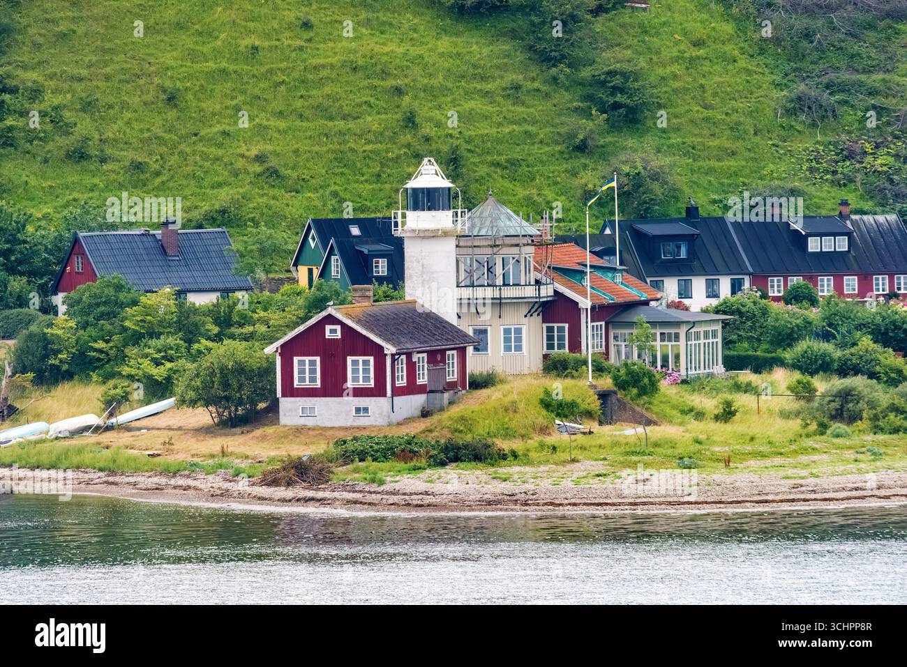 Phare de Hakens Fyr Ven Suède // VEN, Suède — le phare de Hakens fyr, situé sur le promontoire oriental de l'île de Ven, dans le détroit de Öresund, est une aide active à la navigation. Construit à l'origine comme une tour octogonale en bois en 1890, il a été remplacé en 1939 par l'actuelle tour cylindrique blanche en béton, qui mesure 12,5 mètres (41 pieds) de haut. Le phare a été électrifié en 1940 et automatisé en 1961, reflétant les efforts de modernisation du réseau de phares suédois. Hakens fyr est historiquement significatif en tant que premier phare au monde à utiliser une corne de brume tyfon en 1923, remplacée par la suite par b. Banque D'Images
