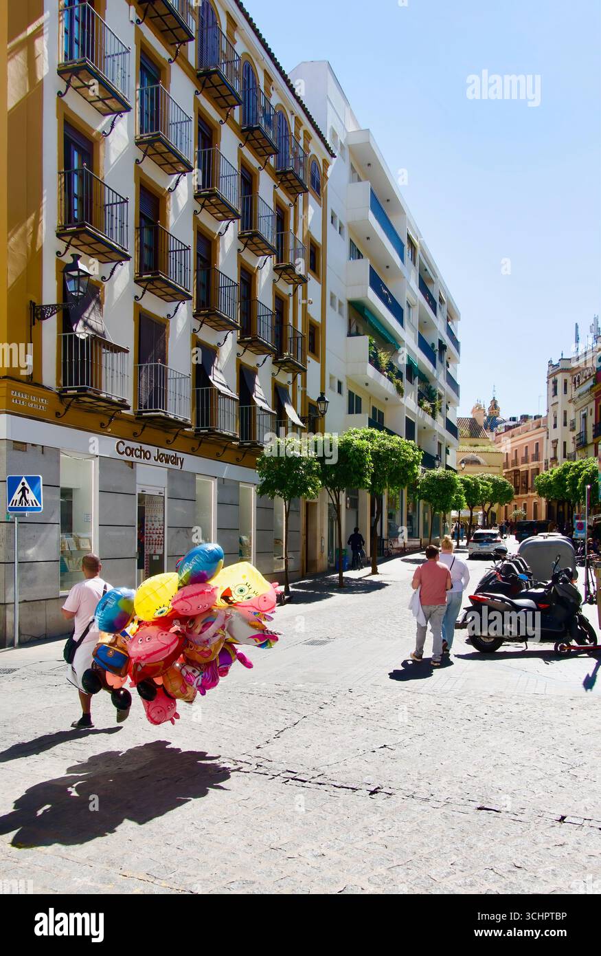 Vendeur de ballons marchant avec des ballons gonflés à vendre dans une rue avec des touristes dans le centre-ville de Séville Andalousie Espagne Europe Banque D'Images