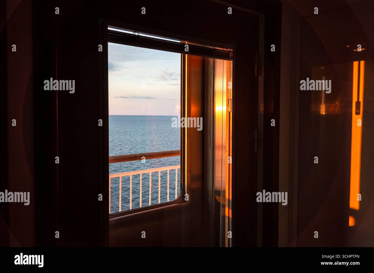 Copenhague à Oslo Ferry au lever du soleil Skagerrak Suède // Strömstad, Suède — la vue depuis une fenêtre sur un ferry voyageant entre Copenhague et Oslo au lever du soleil sur le détroit de Skagerrak. La ligne de ferry relie la capitale du Danemark à la capitale de la Norvège, en passant par le Skagerrak, la partie nord-est de la mer du Nord, qui sépare la Norvège du Danemark et de la côte ouest de la Suède. Ce voyage offre des vues panoramiques sur la côte scandinave et la mer. Banque D'Images