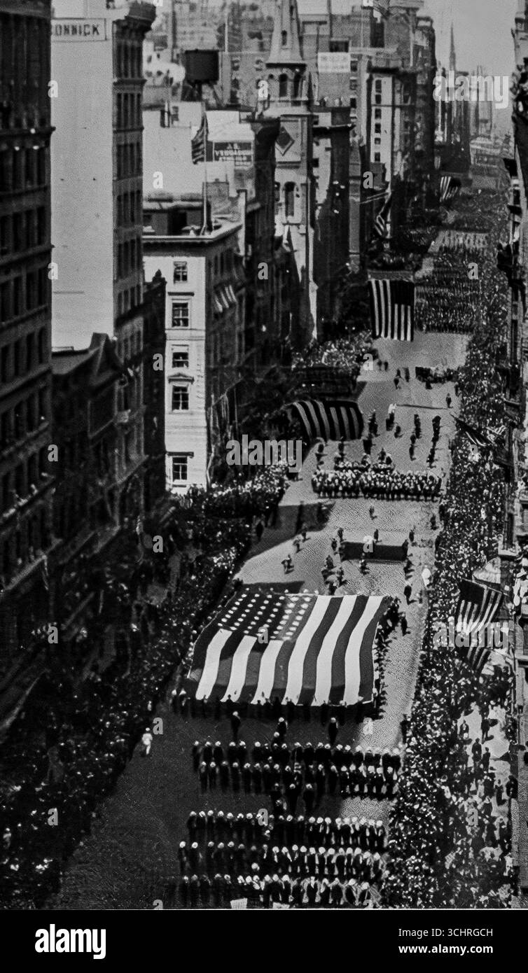Photographie d’un défilé patriotique sur la Cinquième Avenue, New York, montrant un drapeau américain massif porté par le Carpet Club, publiée dans L’illustration, 17 juin 1916. La scène met en lumière les manifestations publiques américaines de fierté nationale pendant la première Guerre mondiale, avant l’entrée officielle de l’Amérique en 1917. Les foules bordent l'avenue alors que des groupes de musique, des soldats et des groupes civiques défilent sous les imposants bâtiments de Manhattan, symbolisant l'unité américaine et l'implication croissante dans les affaires mondiales. Banque D'Images