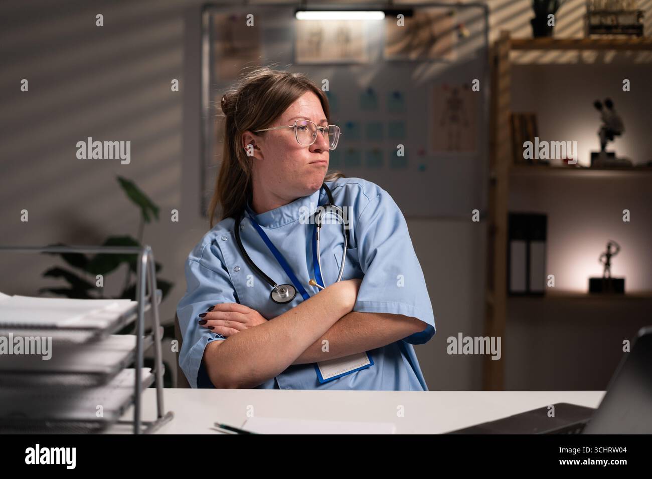 Infirmière en colère travaillant des heures supplémentaires la nuit a croisé les bras sur la poitrine en émotion négative au cabinet hospitalier. Question difficile. Soins de santé et médecine servis Banque D'Images