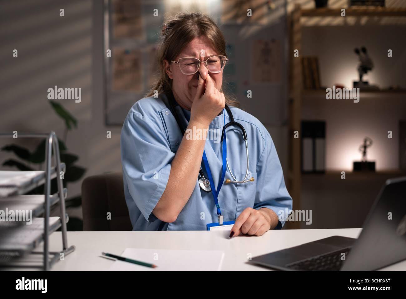 Infirmière fatiguée et stressée travaillant pendant des heures à l'expertise médicale dans le bureau de l'hôpital, dactylographiant le rapport du patient sur ordinateur. Assistant examinant Medi Banque D'Images
