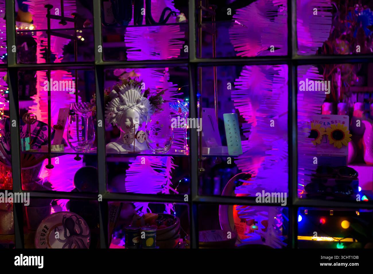 Une vitrine de magasin à Saffron Walden, Essex, la nuit. La scène colorée est éclairée par un éclairage violet et rose vif. Banque D'Images