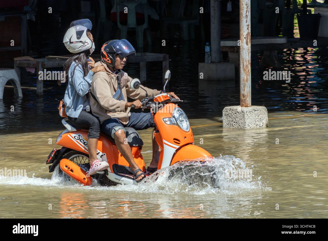 SAMUT PRAKAN, THAÏLANDE, 19 nov 2024, Un couple à moto patente dans une rue inondée Banque D'Images