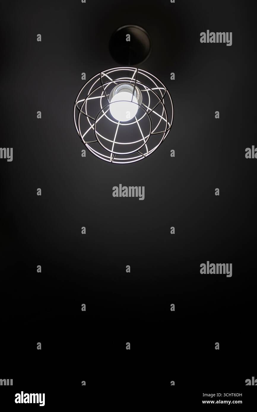 Un luminaire en cage fixé à un plafond dans cette photographie minimaliste en noir et blanc avec espace de copie. Banque D'Images