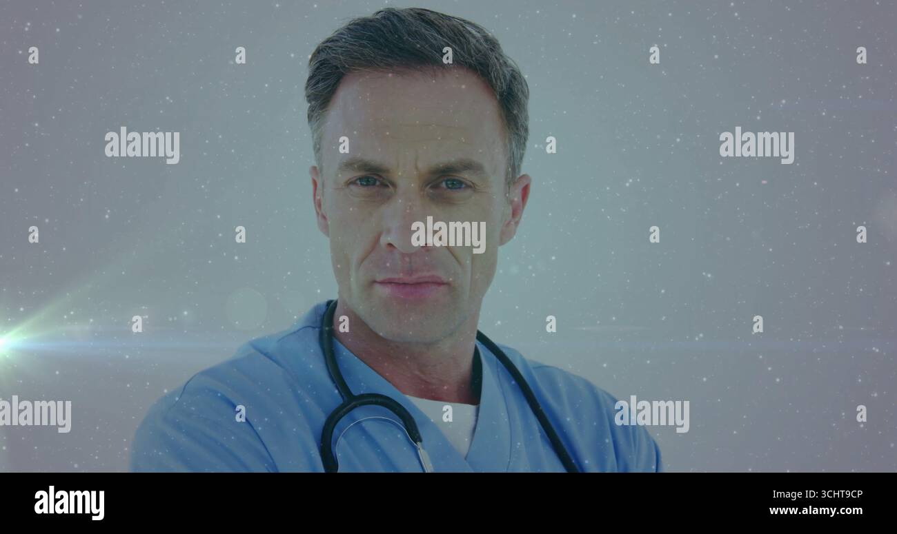 Médecin masculin mature debout face à la caméra en studio, portant des gommages bleu clair et stéthoscope Banque D'Images