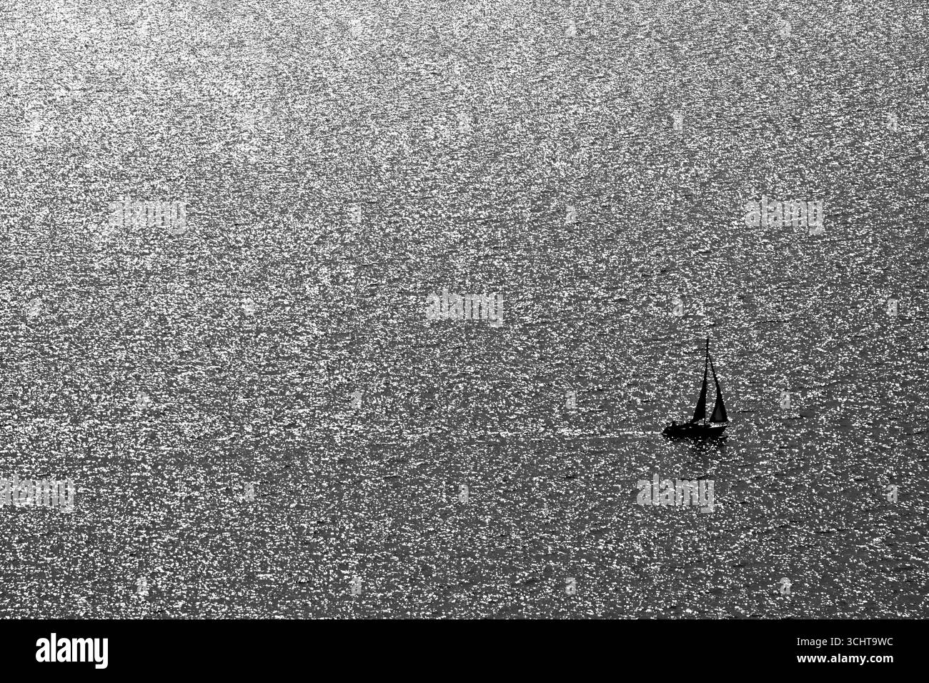 Voilier silhouette sur la surface de l'eau chatoyante en noir et blanc, Tihany, Lac Balaton, Hongrie Banque D'Images