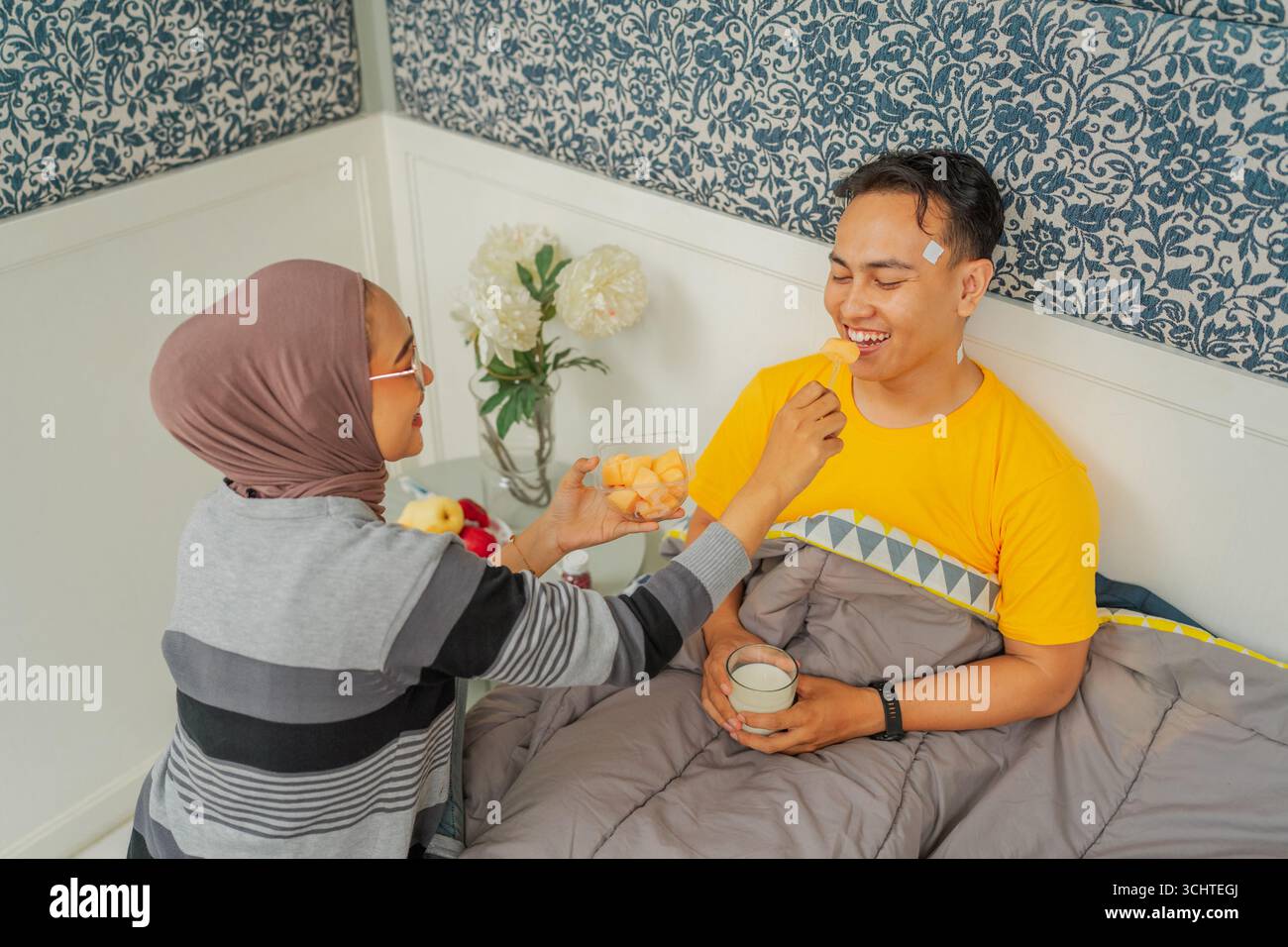 Moment tendre Un couple aimant profite du petit déjeuner au lit, créant des souvenirs spéciaux Banque D'Images