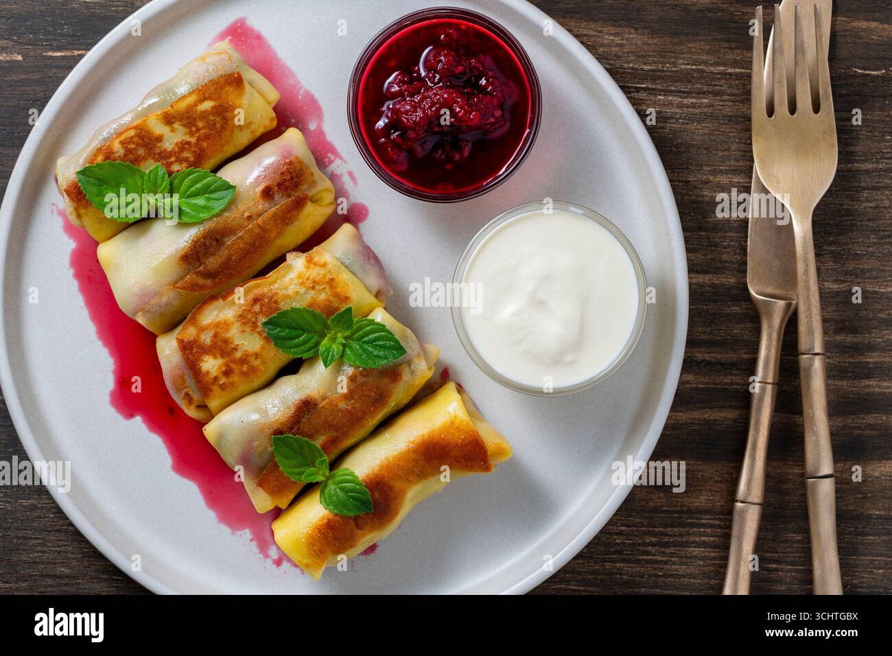 Crêpes roulées frites farcies de fromage cottage et de cerise, dessert sucré sur assiette, gros plan, vue de dessus. Pâtisserie maison. Délicieux fast-food pour bre Banque D'Images