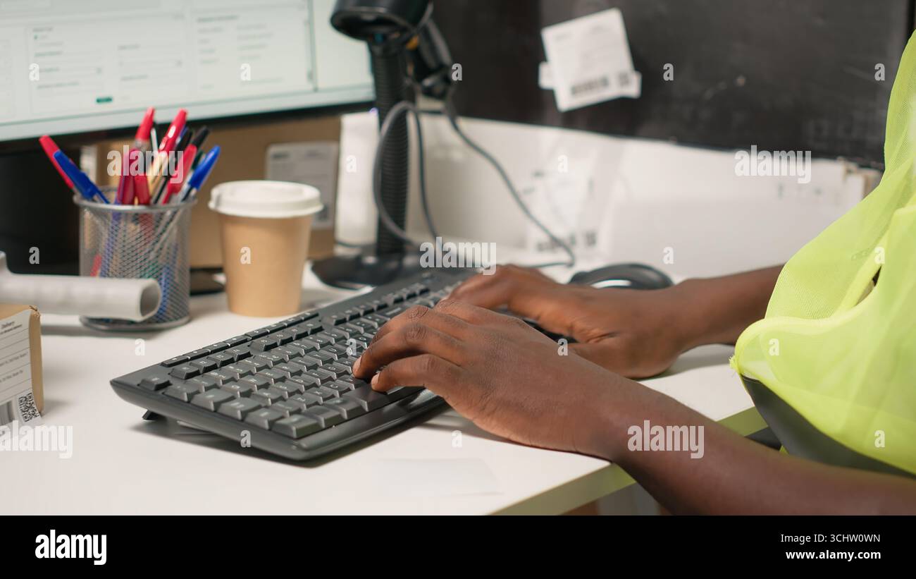 Travailleur afro-américain appliquant les détails de la facture de transport aérien et scannant les étiquettes sur les boîtes. Le suivi des colis, les étiquettes awb et les enregistrements rationalisent les opérations d'expédition pour les grandes entreprises. Caméra B. Banque D'Images