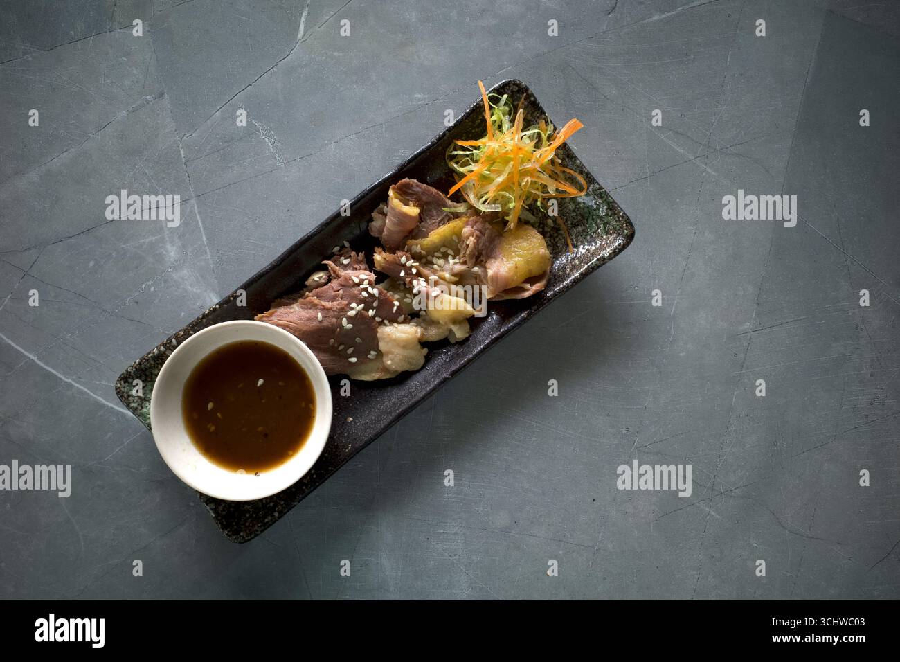 SEI Sapi ou Beef Sei, plat de bœuf fumé traditionnel indonésien et un bol de sauce sur une assiette carrée. Banque D'Images