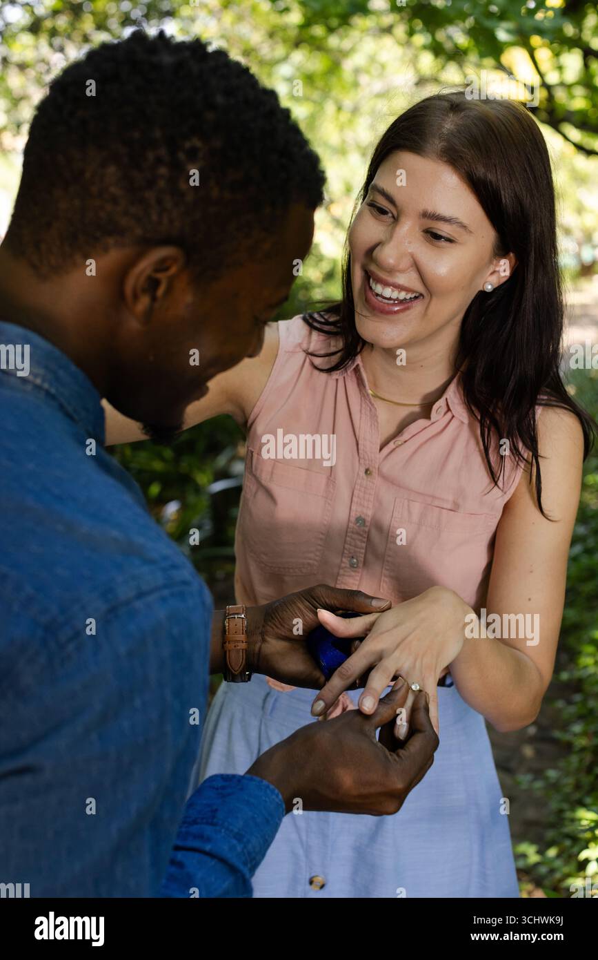 Homme proposant à la femme souriante à l'extérieur, plaçant la bague sur son doigt Banque D'Images