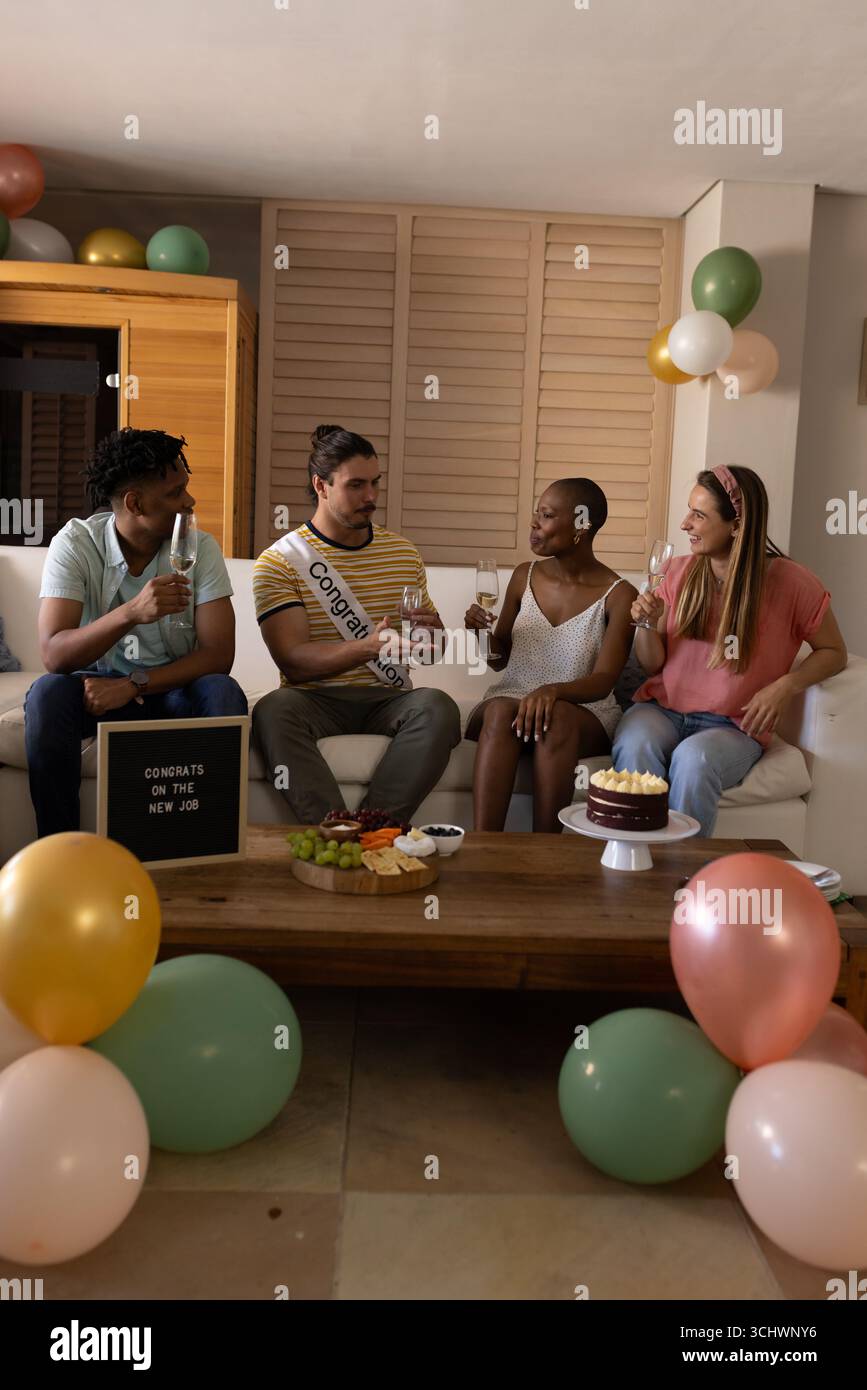 Célébrer un nouvel emploi, divers amis appréciant des boissons et gâteaux à la fête à la maison Banque D'Images