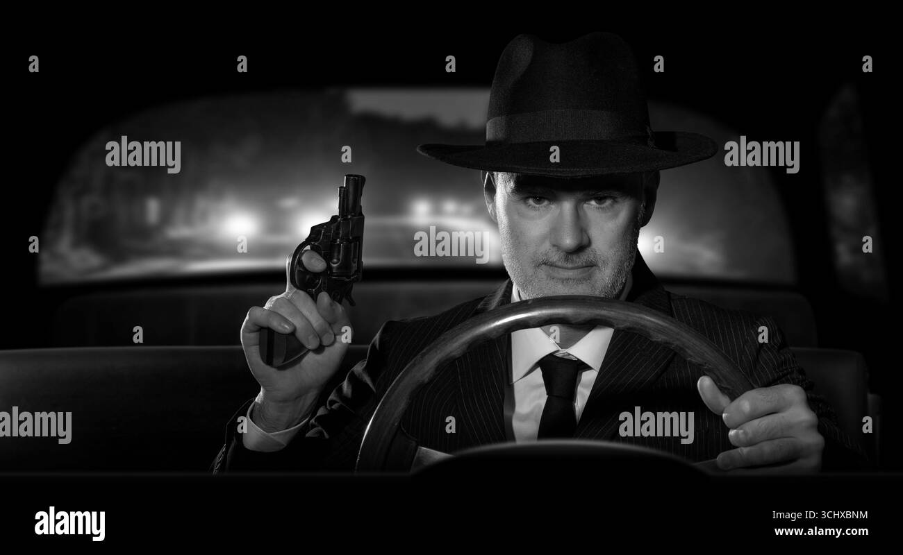 Détective avec une arme à la main poursuivant des criminels dans sa voiture, scène dans le style film noir américain des années 1950. Banque D'Images