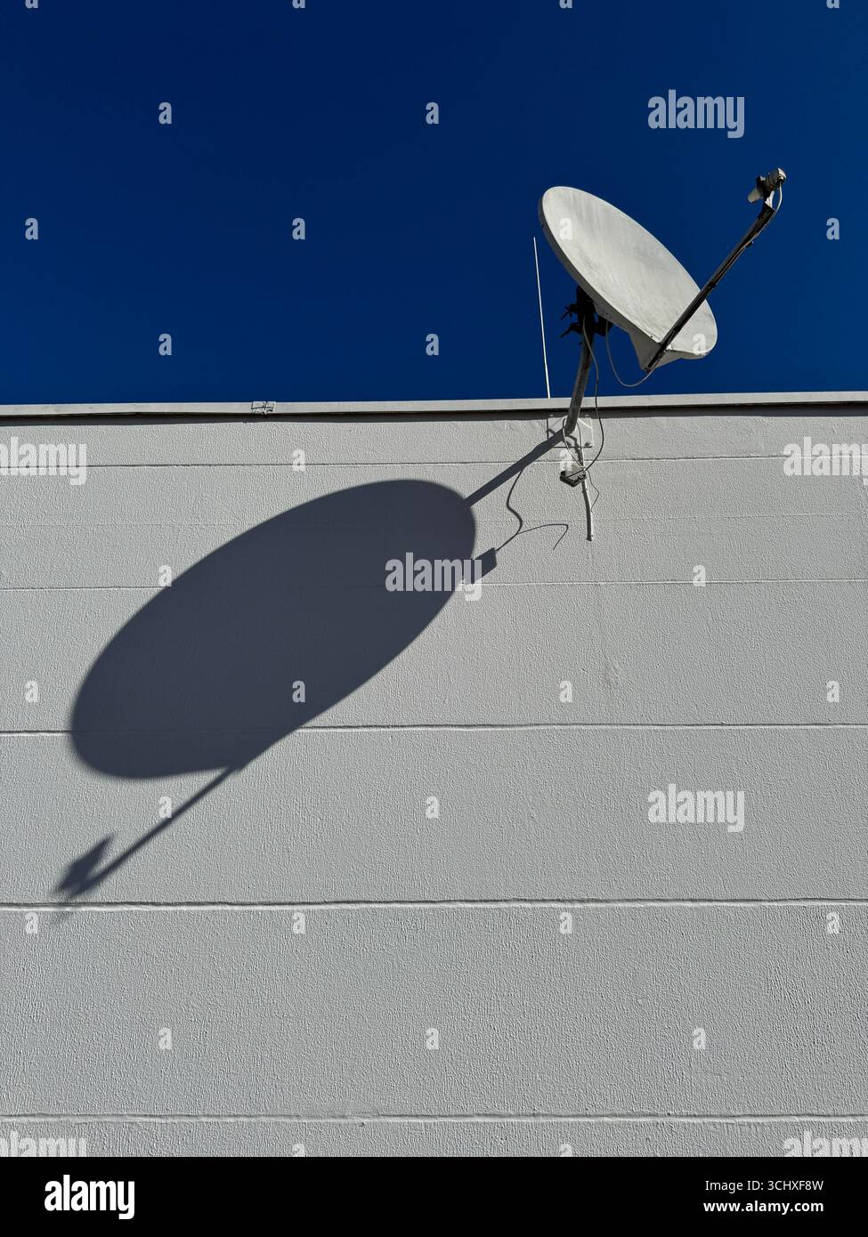 Une antenne parabolique projetant une ombre magnifiquement sur un mur Banque D'Images