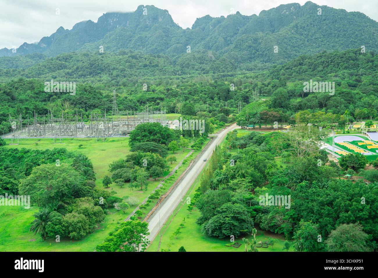 Paysage d'une centrale hydroélectrique entourée de montagnes verdoyantes et de forêts denses, représentant une infrastructure d'énergie renouvelable. Banque D'Images